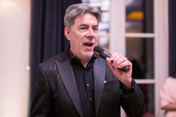 Chris Légendes en costume noir, chantant au micro