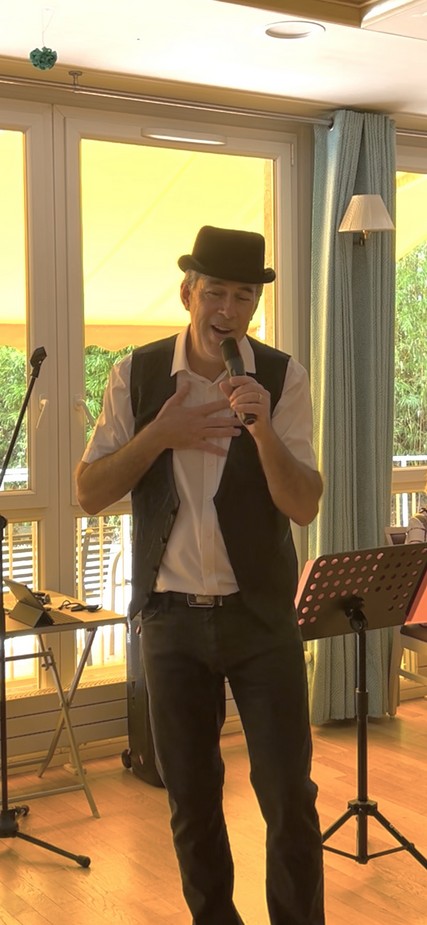 Chris en gilet et chapeau pendant le spectacle d’imitations Jardin d’Hiver